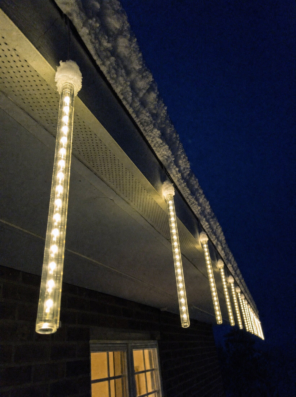 Meteor lights hanging from a house eave like glowing icicles